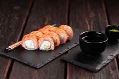寿司卷费城大马哈鱼黄瓜奶油奶酪黑色的背景寿司菜单日本食物概念