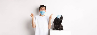 科维德动物检疫概念年轻的男人。黑色的狗穿医疗面具哈巴狗上左角落里老板显示促销提供欢乐