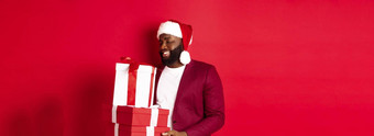 圣诞节一年购物概念快乐非洲amaerican男人。感动了感激圣诞节礼物接收礼物穿圣诞老人他红色的背景
