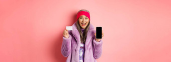 特殊的促销活动兴奋亚洲<strong>高级</strong>女人显示空白智能手机屏幕塑料信贷卡检查在线提供粉红色的背景
