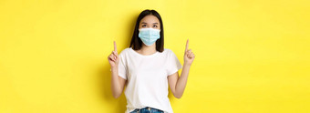 科维德流感大流行社会距离概念年轻的亚洲女人白色t恤医疗面具冠状病毒指出手指显示特殊的提供