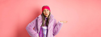 时尚购物概念时尚的亚洲高级女人紫色的冬天装展示产品手很酷的夫人时尚的衣服持有棕榈粉红色的背景