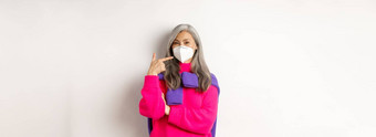 科维德流感大流行社会距离概念时尚亚洲高级女人穿呼吸器指出脸面具微笑站白色背景