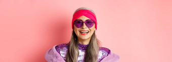 时尚关闭时尚的高级女人微笑快乐相机穿太阳镜迪斯科头巾粉红色的背景