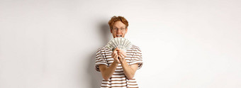 购物金融概念幸运的红色头发的人的家伙赢得显示奖钱微笑快乐站眼镜t恤白色背景