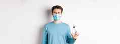 科维德健康检疫概念肖像微笑男人。医疗面具显示手洗手液瓶站白色背景