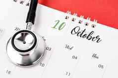 听诊器医疗10月桌子上日历红色的背景时间表检查健康的概念