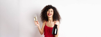 快乐聚会，派对女人红色的衣服笑持有瓶香槟玻璃喝有趣的庆祝假期站白色背景