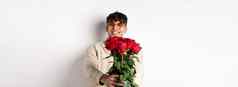 英俊的的男朋友给花束玫瑰使惊喜礼物浪漫的日期情人节一天站情人白色背景