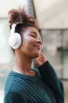 年轻的黑色的女人听音乐在线穿无线耳机享受最喜欢的首歌播放列表音乐应用程序