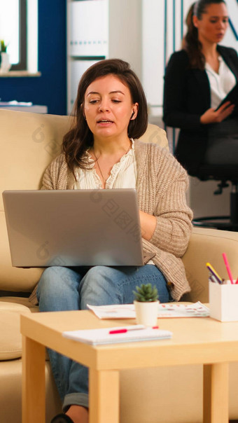 业务女人会说话的<strong>视频</strong>会议调用移动PC坐着沙发上