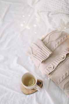 针织米色毛衣杯茶混乱的床上背景冬天春天时尚概念前视图平躺