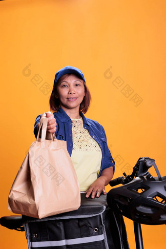 亚洲比萨 店工人持有回收纸袋交付食物客户端