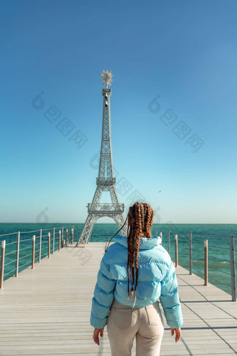 大模型埃菲尔铁塔塔海滩女人走码头塔穿蓝色的夹克白色牛仔裤