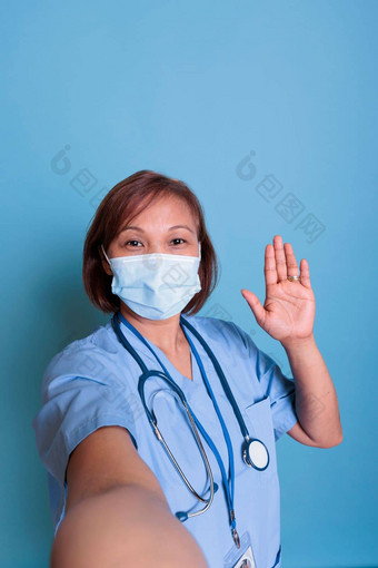 亚洲上了年纪的护士穿保护脸面具防止感染科维德