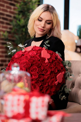 女人持有红色的玫瑰花束模糊giftboxes表格