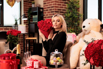 女人坐着大熊礼物持有红色的玫瑰花束