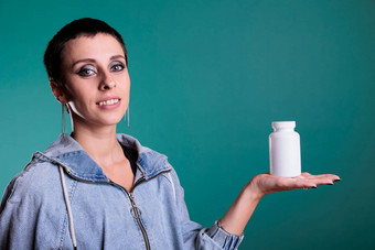 微笑浅黑肤色的女人女人短头发持有瓶药物展示健康护理产品相机