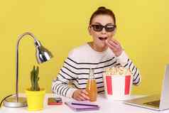 女人眼镜吃爆米花饮料坐着工作场所享受有趣的电影