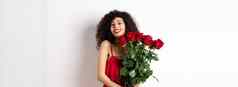 浪漫的夫人卷曲的头发时尚衣服持有花束红色的玫瑰微笑站快乐白色背景