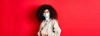 科维德流感大流行检疫概念时髦的女孩沟外套医疗面具把沟外套春天<strong>走红</strong>色的背景