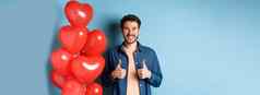 快乐情人节一天快乐的的男朋友显示拇指批准站红色的心气球情人蓝色的背景