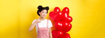 时尚亚洲女人浪漫的装化妆显示拇指微笑赞扬情人节一天提供站红色的心气球黄色的背景