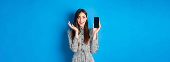 兴奋女孩显示空智能手机屏幕喘气着迷演示购物应用程序站蓝色的背景