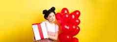 快乐情人节一天美丽的时尚的亚洲女人摆姿势心气球可爱的盒子礼物情人站黄色的背景