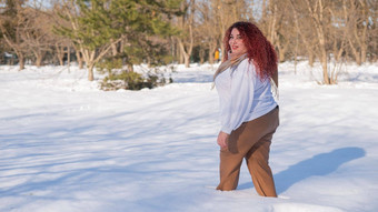 脂肪红发女人白色运动衫走雪地里