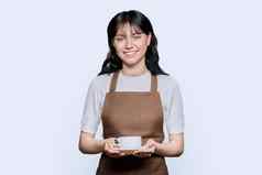 年轻的微笑女女服务员围裙咖啡杯白色背景