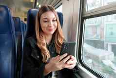 美丽的学生女孩坐着火车智能手机