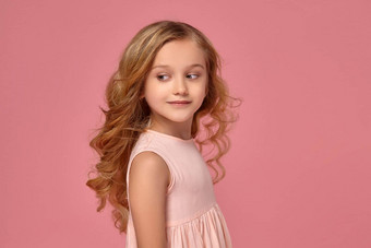 女孩金发碧眼的卷曲的头发粉红色的衣服摆姿势相机