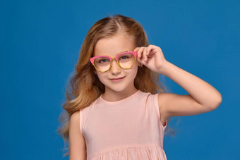 时尚女孩粉红色的衣服眼镜站蓝色的背景