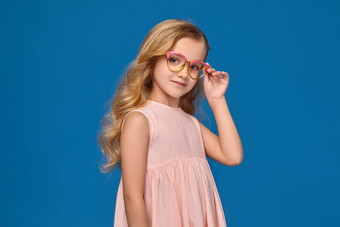 时尚女孩粉红色的衣服眼镜站蓝色的背景