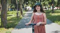 肖像女孩电踏板车摆姿势公园夏天