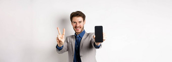 电子商务在线购物概念快乐的男人。业务西装显示地摆空移动电话屏幕演示智能手机应用程序白色背景