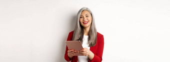 业务成功的高级女商人工作数字平板电脑微笑站红色的夹克白色背景