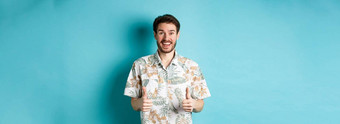 夏天假期兴奋微笑旅游夏威夷衬衫显示竖起大拇指赞扬酒店假期的地方站蓝色的背景