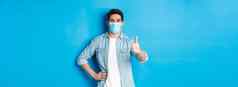 概念科维德流感大流行社会距离满意的家伙医疗面具显示拇指批准站蓝色的背景
