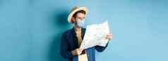 科维德流感大流行旅行概念英俊的年轻的的家伙脸面具夏天他旅游地图旅行假期站蓝色的背景