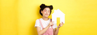 真正的房地产家庭概念梦幻微笑亚洲女人明亮的化妆显示纸房子断路关闭眼睛做白日梦购买财产黄色的背景