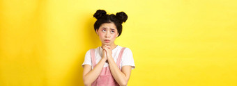 情景应用程序亚洲女孩持有手祈祷恳求神乞讨站黄色的背景