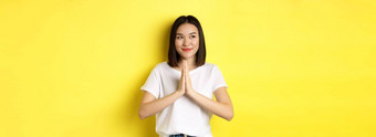 漂亮的亚洲女人持有手纳马斯特祈祷手势左微笑表达感激之情站黄色的背景