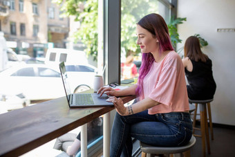 一边视图年轻的女商人坐着表格咖啡商店表格杯咖啡移动PC背景白色墙窗口