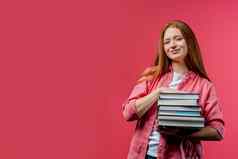 聪明的学生持有堆栈大学书大学图书馆粉红色的背景快乐红发女孩微笑快乐研究生复制空间
