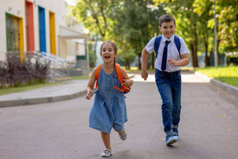 快乐的小学生女孩男孩白色衬衫背包运行学校