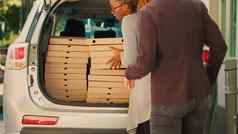 比萨 店员工给桩披萨盒子多样化的客户
