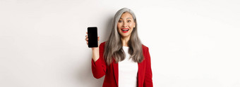 快乐的亚洲女企业家显示移动电话屏幕微笑逗乐站白色背景
