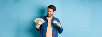 微笑现代的家伙现金显示塑料信贷卡站蓝色的背景